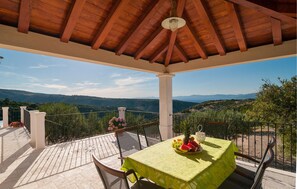 A covered outdoor area with a table set for dining, overlooking a scenic landscape. - Beautiful home in Postira (Postira)