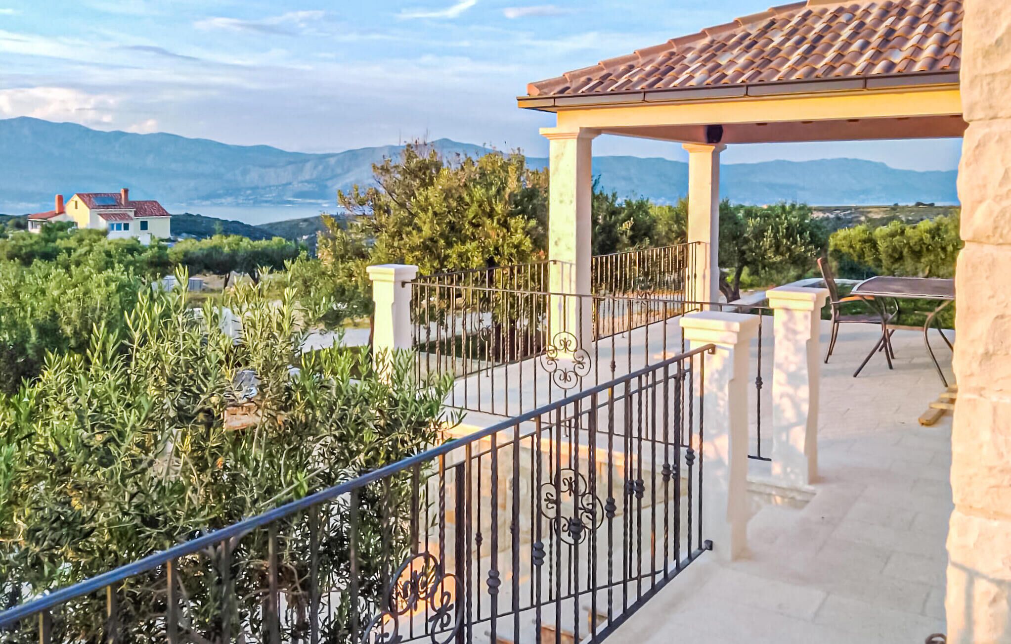 A balcony with a view of mountains, a pergola, and a seating area.