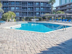 Une piscine équipée de chaises longues et d’un panneau indiquant qu’il est interdit de plonger.