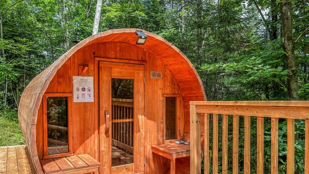 Eine Holzsauna mit gewölbtem Dach, einer Holzterrasse und einem Hollerleger.
