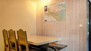Ein Zimmer mit Holzwänden, einem Tisch, Stühlen, einer Karte an der Wand und einer Tür.