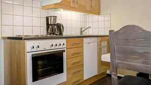 Eine kleine Küche mit Einbauofen, Kaffeemaschine und Holzausbau.