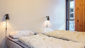 Ein Schlafzimmer mit zwei Betten, jeweils mit weißer Bettdecke und Kissen, sowie zwei Wandlampen.