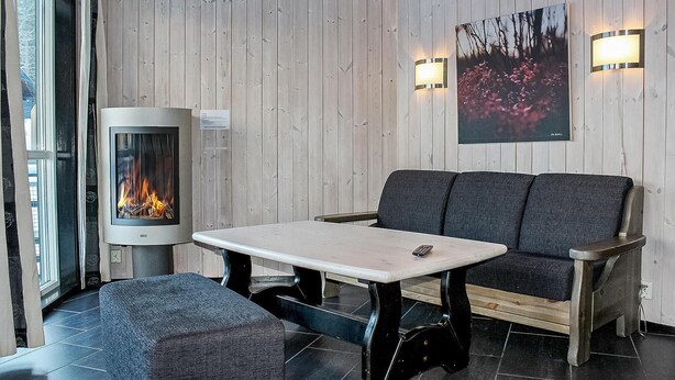 Ein gemütliches Zimmer mit Kamin, einer Couch, einem Tisch und einer Bank.