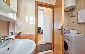 A modern bathroom with a sink, toilet, and washing machine.