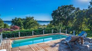 A wooden deck with a pool, lounge chairs, and a view of a lake and hills. - Amazing home in Caprarola with kitchen (Caprarola)
