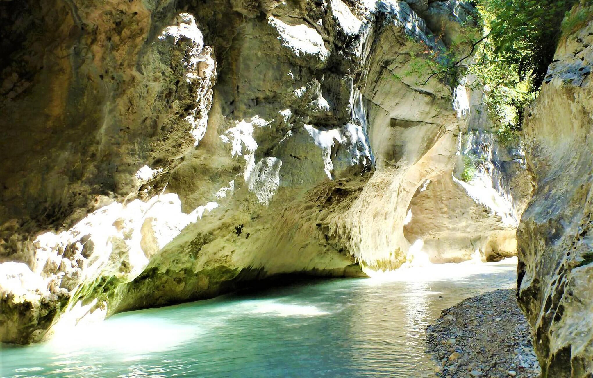 A natural cave with a clear water pool and rocky walls.