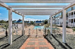 A covered outdoor area with a pool, lounge chairs, and a view of buildings. - 6 Seater Golf Cart, 3 Bikes, Easy walk to Beach! (Santa Rosa Beach)