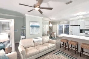A modern kitchen with white cabinets, a central island, and bar stools. - 6 Seater Golf Cart, 3 Bikes, Easy walk to Beach! (Santa Rosa Beach)