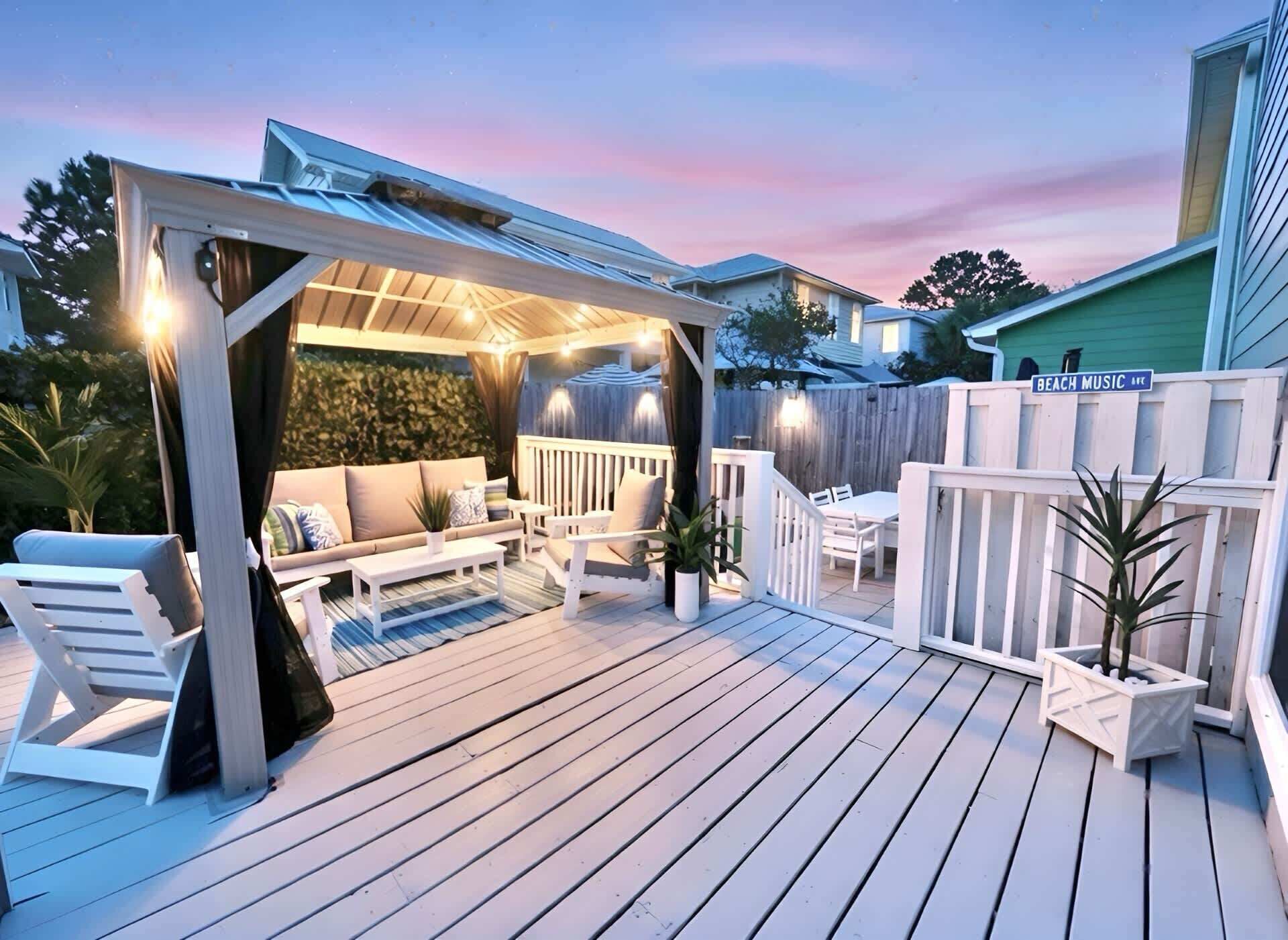 A covered outdoor patio with seating, a pergola, and a wooden deck.