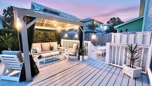 Eine überdachte Terrasse im Freien mit Sitzgelegenheiten, einer Pergola und einem Holzboden.