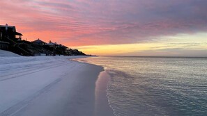 A beach with a sunset, a sandy shore, and buildings in the background. - 6 Seater Golf Cart, 3 Bikes, Easy walk to Beach! (Santa Rosa Beach)
