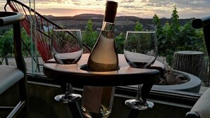 A table with a bottle and glasses, overlooking a scenic landscape with hills and a sunset. - Hotel Boutique Kpricho (SAN Antonio de las Minas)