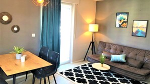 Un salon comprenant un canapé, une table à manger avec des chaises, une lampe et un tapis à motifs.