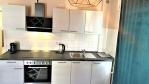 Une cuisine moderne avec des meubles blancs, un four encastré, une machine à café et un évier.