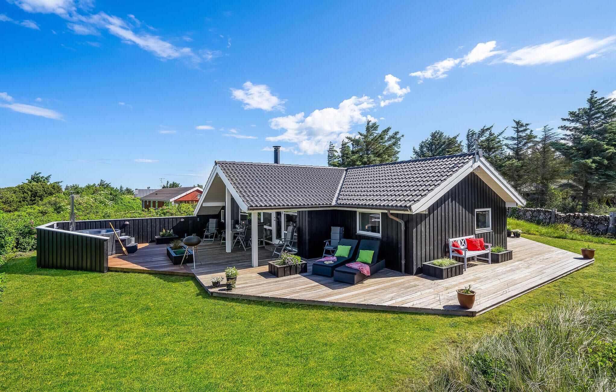 A modern house with a deck, outdoor seating, and a barbecue area.