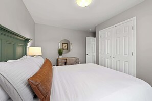 Une chambre à coucher bien rangée, avec un lit, une table de chevet, une lampe et un miroir.