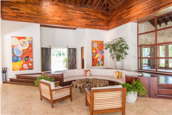 Amplia sala de estar con techo de madera, un ventanal grande y un sofá blanco.