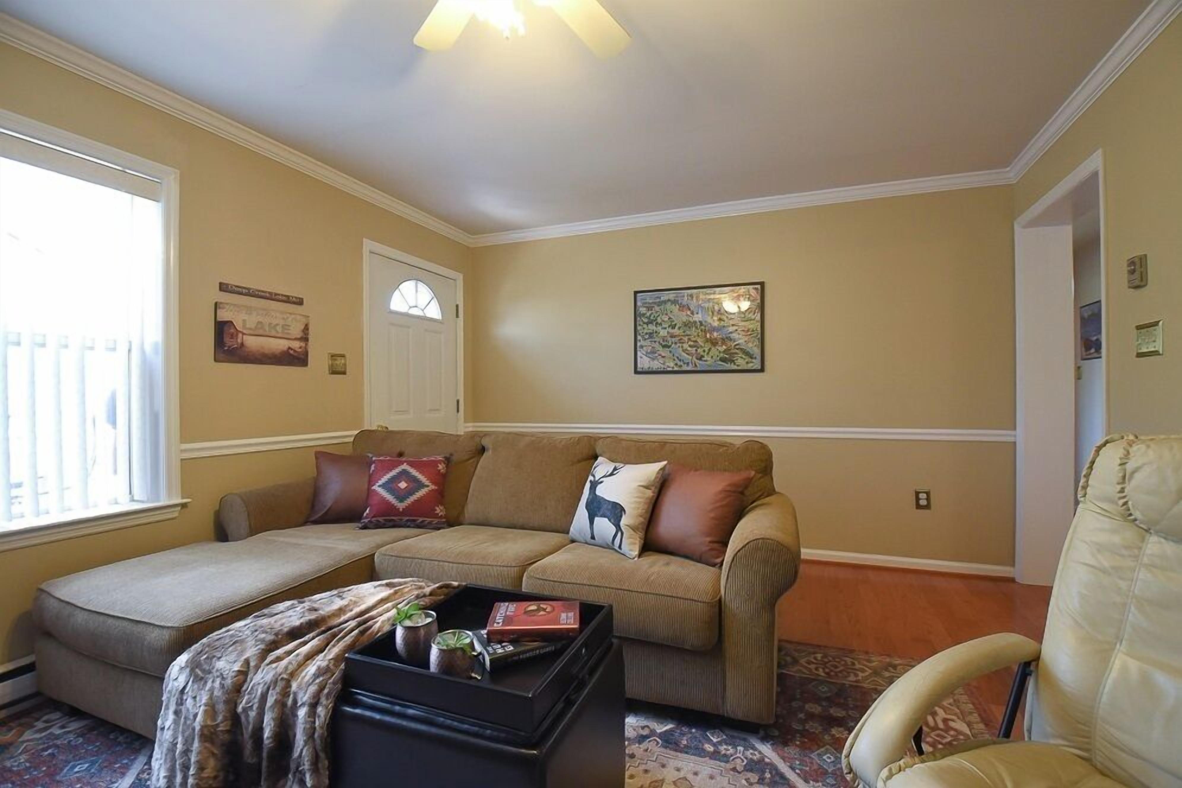 A living room with a beige sofa, a small couch, a coffee table with books, and a chair.