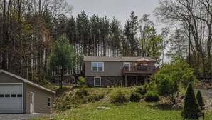 Uma casa de dois andares com garagem, varanda e fachada de pedra.