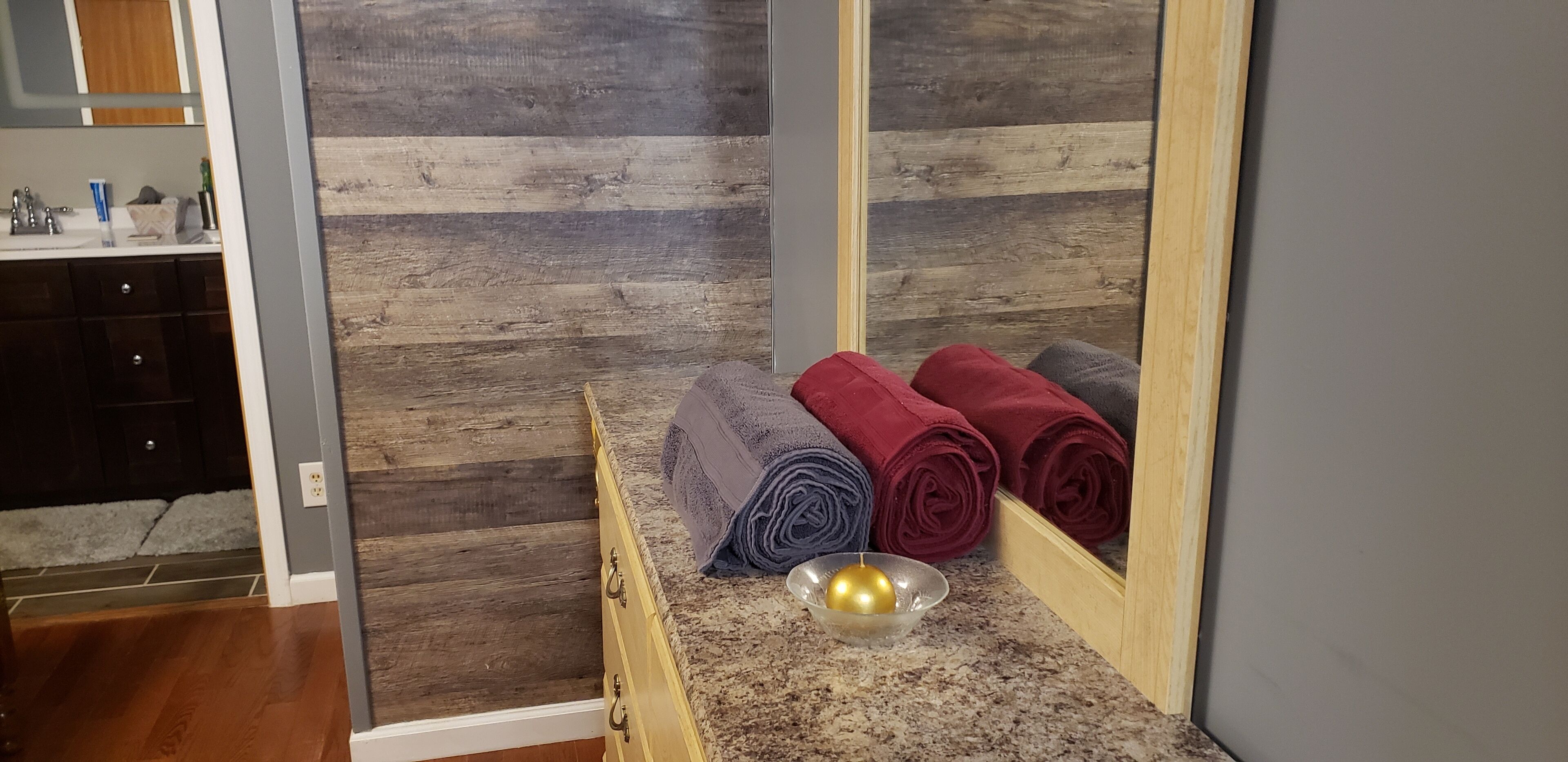 Une salle de bain avec un mur en bois, un lavabo avec des articles de toilette et des serviettes posées sur un comptoir.