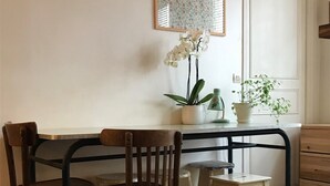 Ein Essbereich mit Holztisch und -stühlen, einer Topfpflanze und einem gerahmten Bild an der Wand.