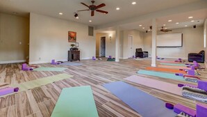A spacious room with wooden flooring, multiple yoga mats, and purple foam blocks arranged for exercise.