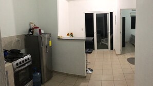Cocina compacta equipada con refrigerador, estufa y dispensador de agua.
