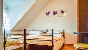 A bedroom with a bunk bed, a small table, and a chair. There are three framed pictures on the wall.