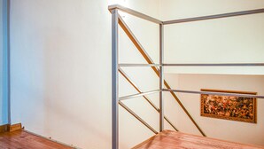 A room with a metal bunk bed, a wooden floor, and a framed painting on the wall.