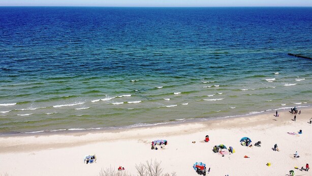 A beach with people and umbrellas, a sandy shore, and the ocean.