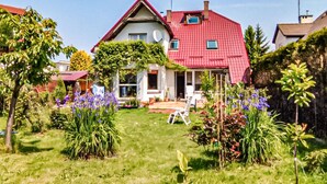 A house with a red roof, a satellite dish, and a garden with various plants and flowers.