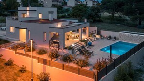 Una casa moderna con piscina, mobiliario de exterior y zona de barbacoa.