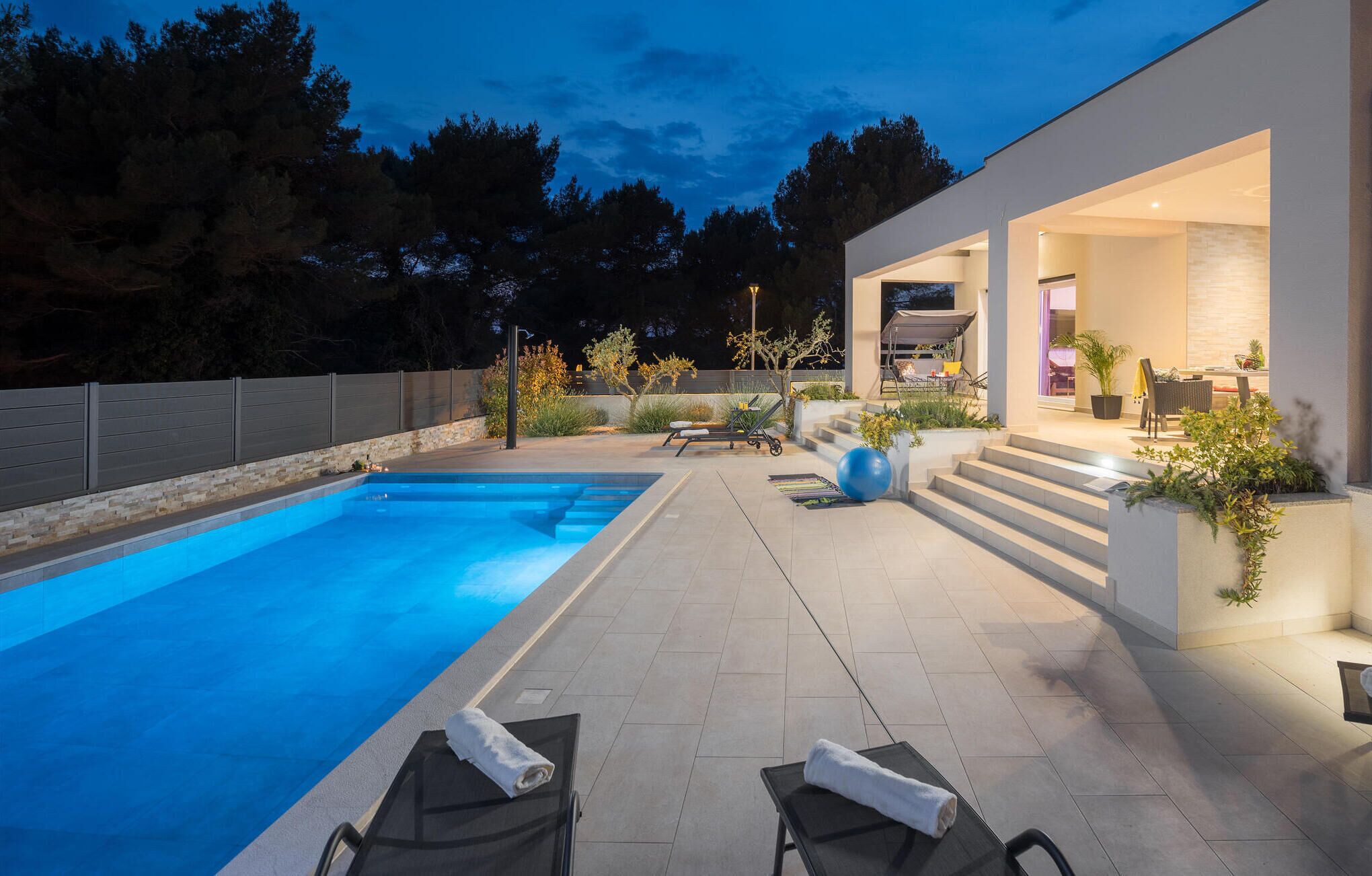 A modern outdoor pool area with lounge chairs and a covered seating area.