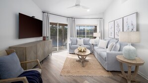 Ein modernes Wohnzimmer mit einem grauen Sofa, einem Holzschrank, einem runden Couchtisch und einem Deckenventilator.
