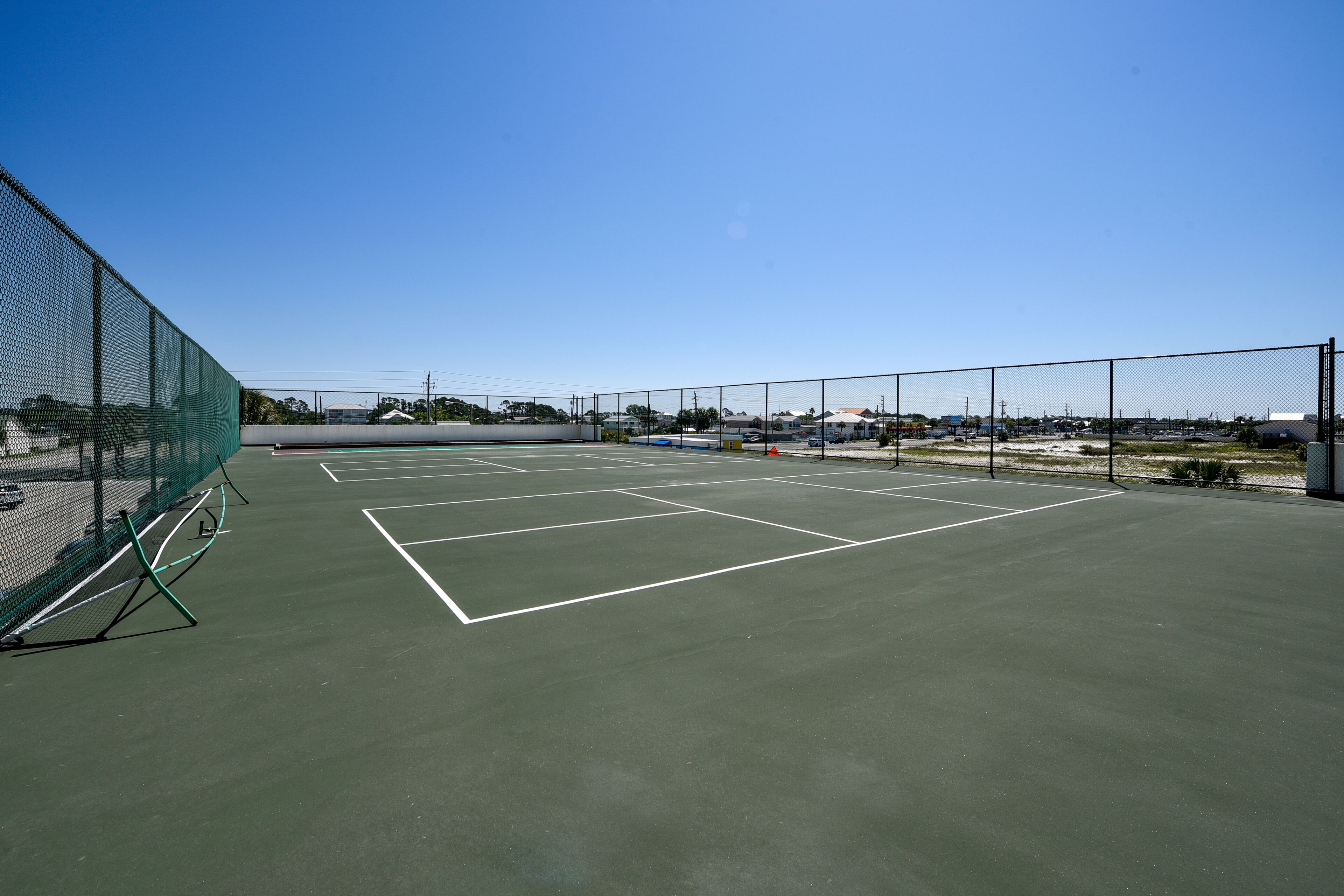 Un court de tennis extérieur doté d’une surface verte et de lignes de démarcation blanches.