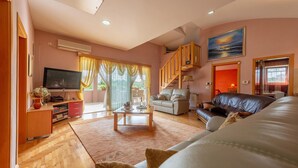 A living room with a sofa, a coffee table, and a TV. There is a staircase leading to another room. - Nice home in Zadar with WiFi (Zadar)