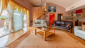 A spacious living room with a wooden coffee table, two sofas, a staircase, and a kitchen area. - Nice home in Zadar with WiFi (Zadar)