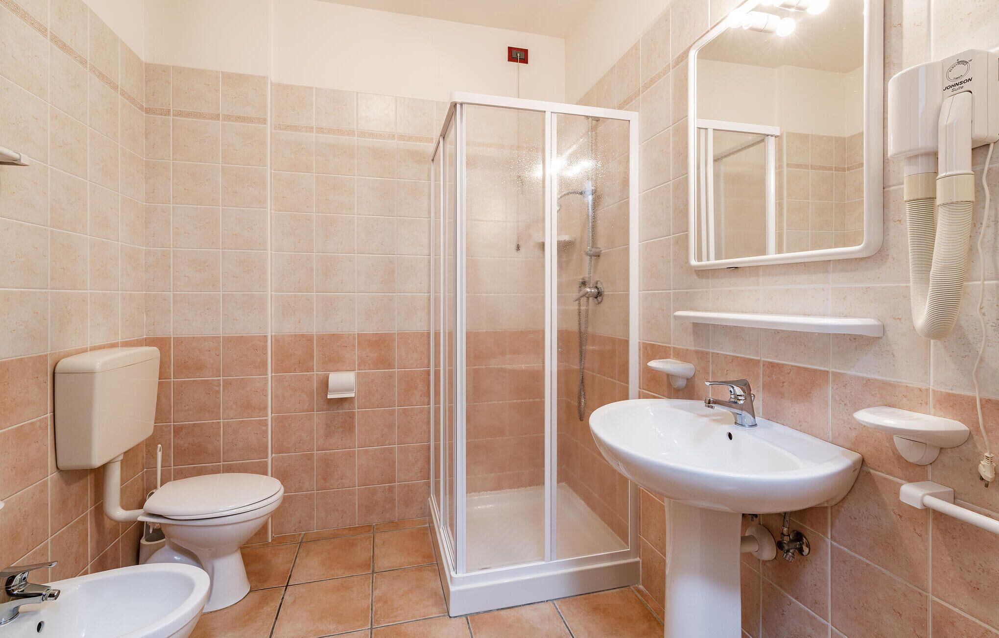 Ein Badezimmer mit Toilette, Bidet, Duschkabine und Waschbecken.