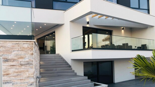 A modern multi-story house with a staircase leading to a balcony.