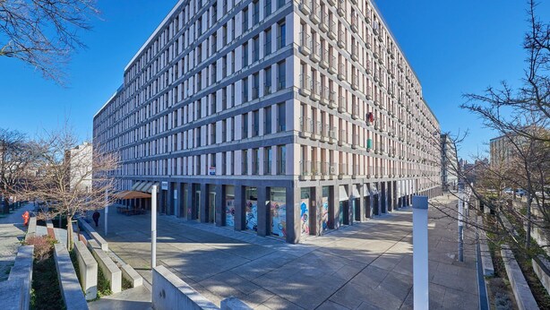 Un edificio moderno con fachada enrejada, grandes ventanales y techo plano.