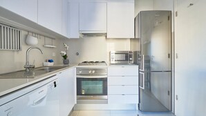 Una cocina moderna con electrodomésticos de acero inoxidable, armarios blancos y horno empotrado.