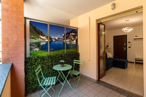 A room with a view of a mountain lake, a small table with chairs, and a door leading to another room.