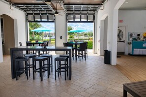 A spacious outdoor seating area with a glass table and chairs, a trash bin, and a fan on the right. - Closest House to Resort • Star Wars Adventure + Home Theater! (Kissimmee)