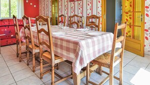 Una mesa de comedor con mantel a cuadros, rodeada de sillas de madera con asientos de mimbre.