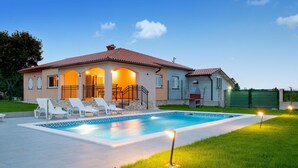Ein Haus mit Swimmingpool, Sitzgelegenheiten im Freien und einem eingezäunten Garten.