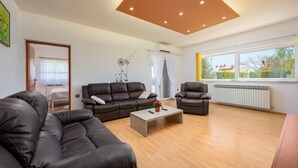 Ein modernes Wohnzimmer mit einer Sofagarnitur, einem Couchtisch und Blick ins Freie.