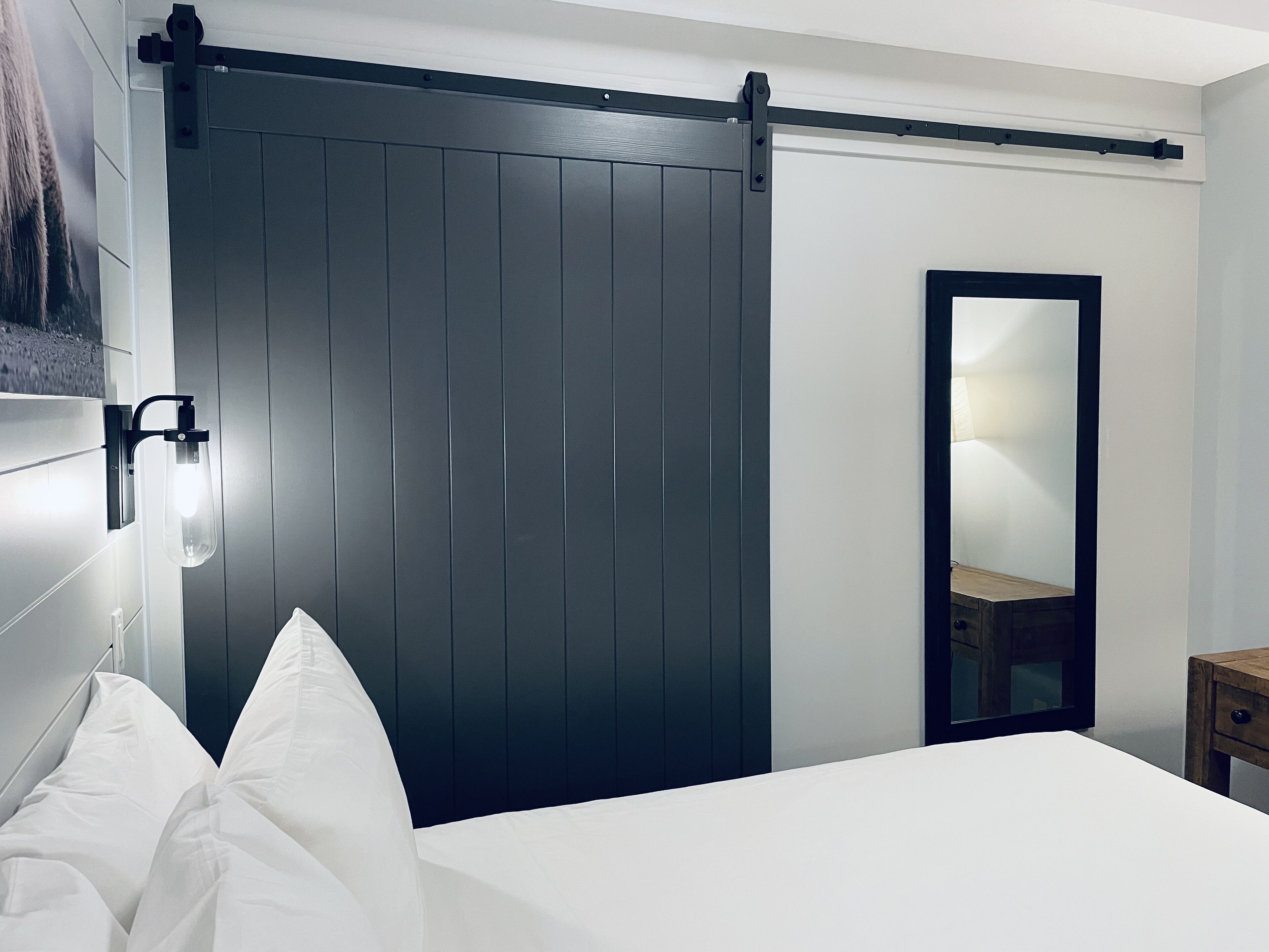 A bedroom with a bed, a sliding door, a bedside table, and a mirror.