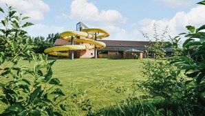 Een gebouw met een opvallende spiraalstructuur in het midden, omringd door een verzorgd gazon en groen.