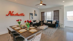 A modern living room with a dining area, a black sofa, and a ceiling fan. - 3 Story, Roof top very close to Broadway 516 (Nashville)